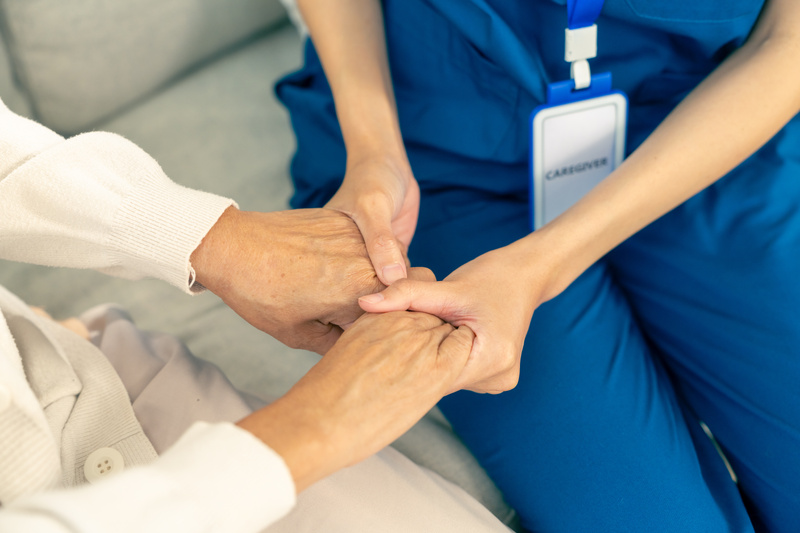 A caregiver holding the hands of a patient